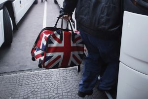 A man carrying a bag adorned with a British Union Jack flag steps into bus departing from Sofia's central bus station to London