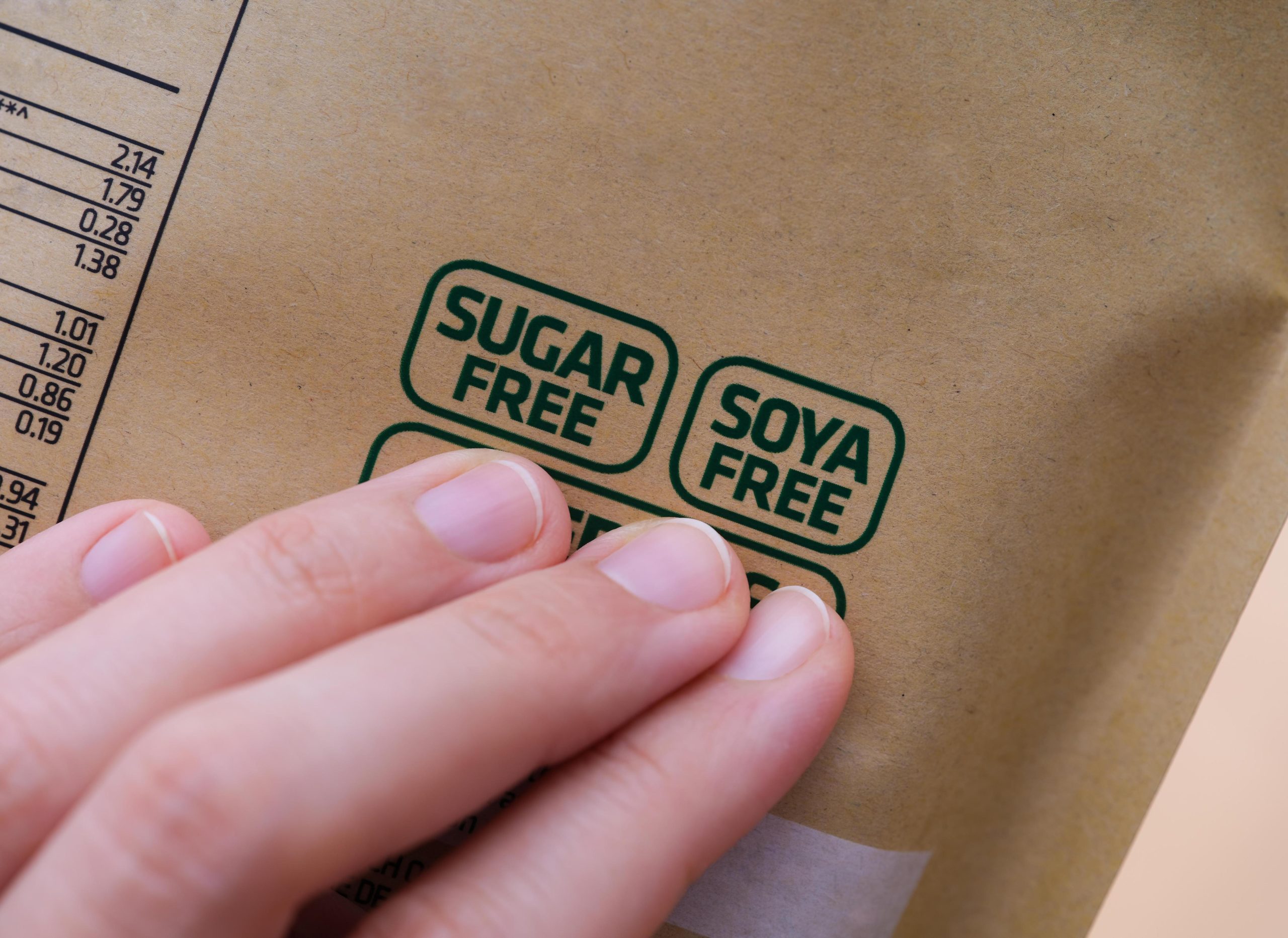 A woman holding a package with a Sugar Free and a Soya Free label on it.